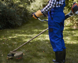 Busy man using a weedwacker at garden